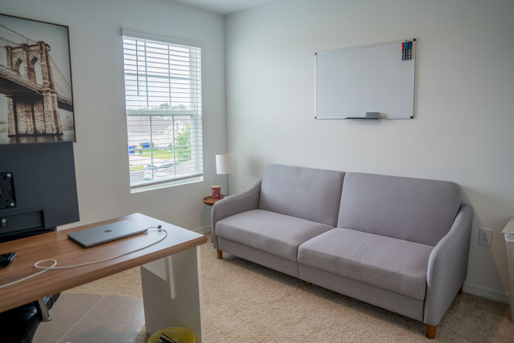 Home office with desk, laptop, sofa and whiteboard