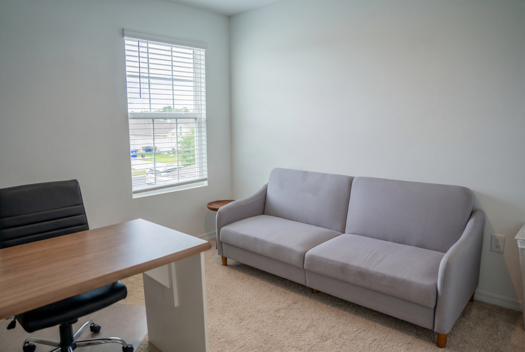 Virtually staged home office with desk and sofa