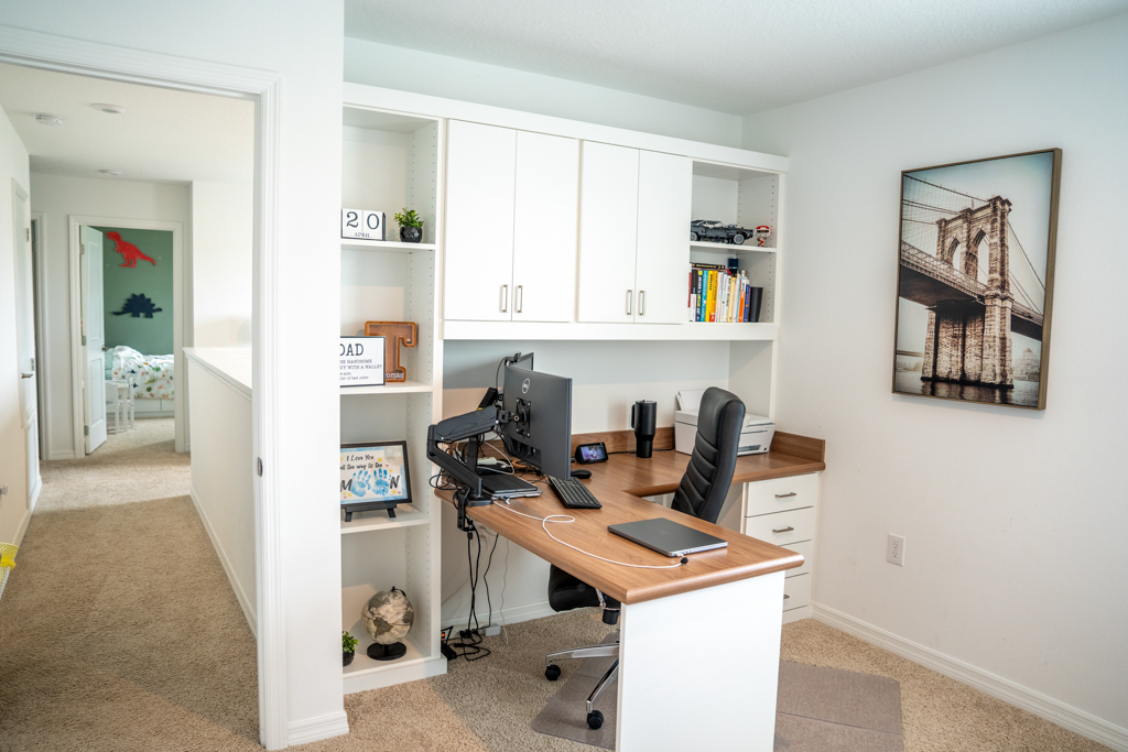Home office with built-in L-shaped desk, dual monitors and upper cabinets