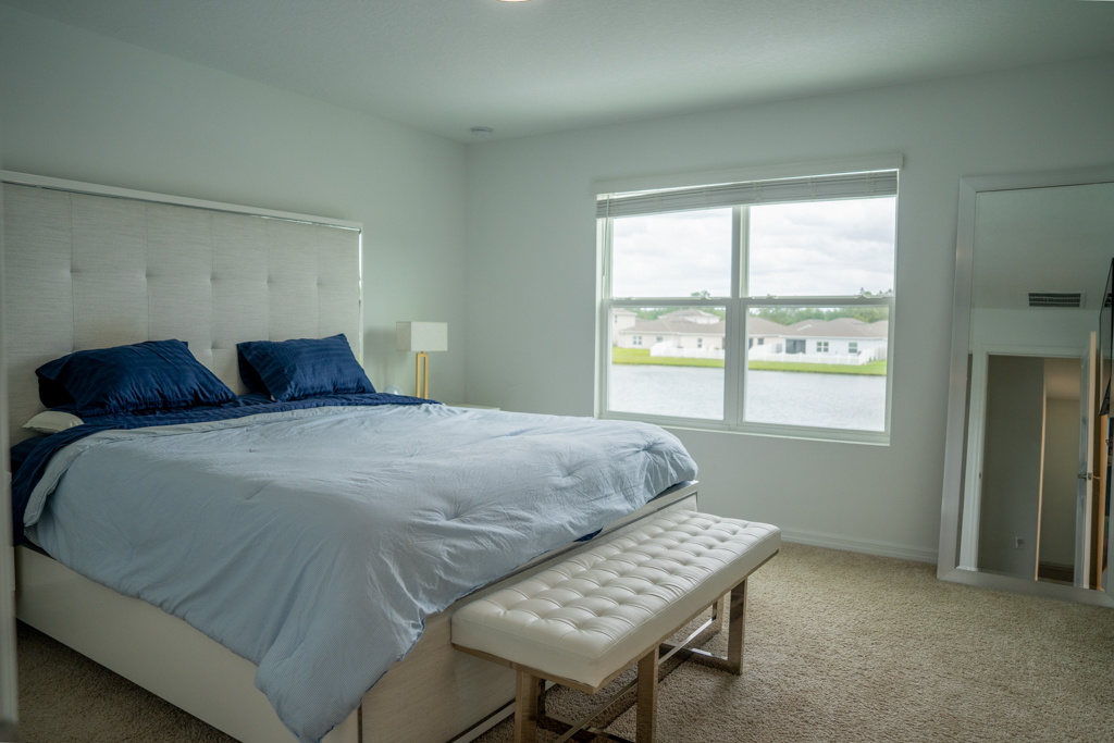 Primary bedroom with tufted headboard, blue bedding and lake view window