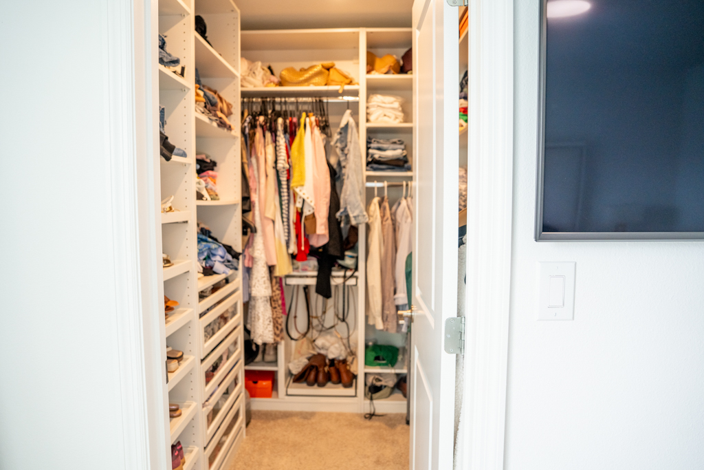 Primary walk-in closet with custom shelving and hanging clothes
