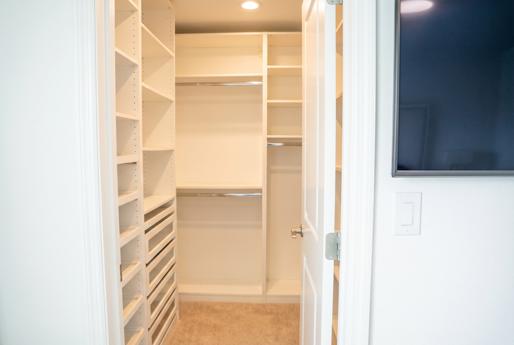 Virtually staged empty primary walk-in closet with custom shelving system