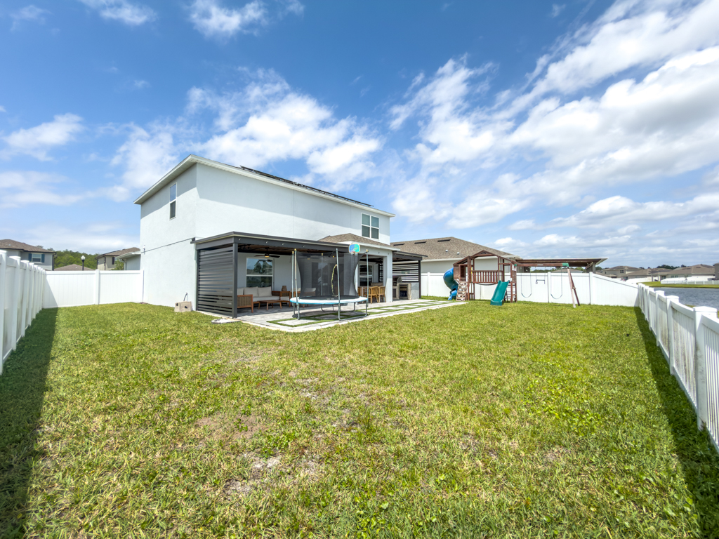 Backyard with spacious lawn, covered pergola patio, trampoline and playground