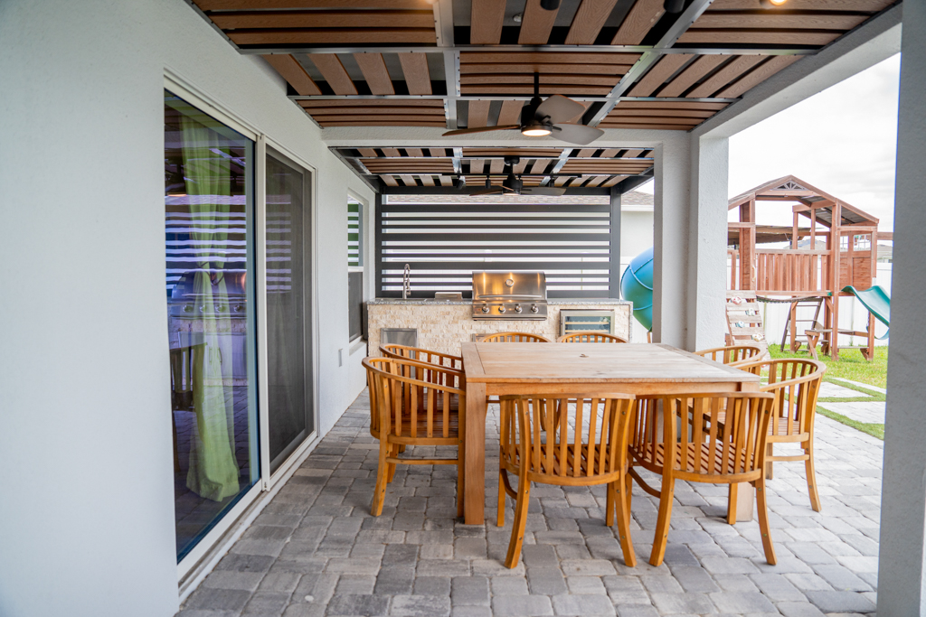 Covered patio with teak outdoor dining table and built-in BBQ grill station