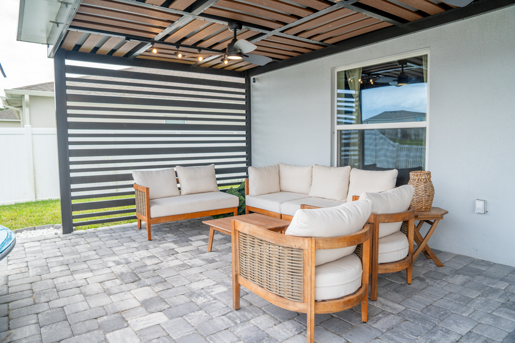 Covered patio outdoor living area with wicker lounge seating set under modern pergola