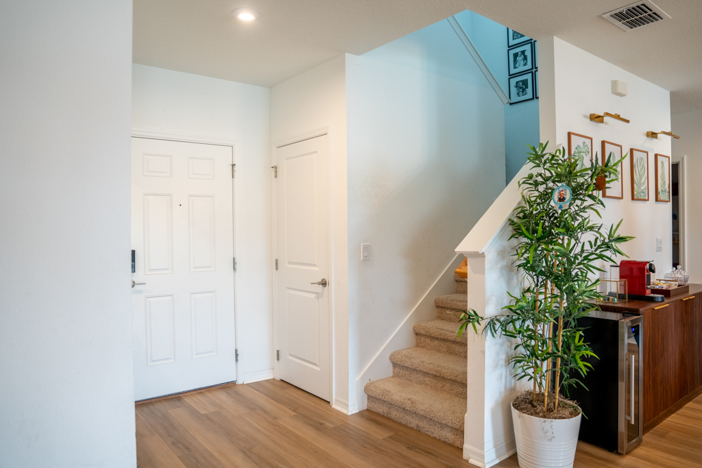 Foyer with staircase, bamboo plant, botanical artwork and wine bar