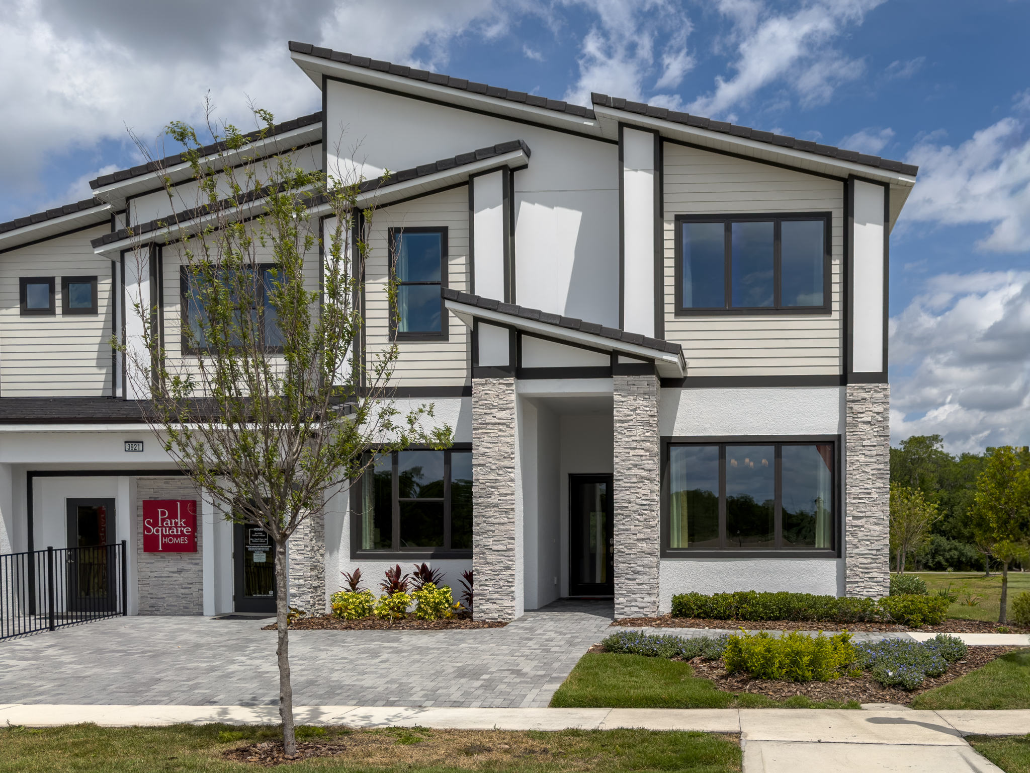 Front exterior of two-story vacation home at Sonoma, Kissimmee, FL with stone accent facade and paver driveway