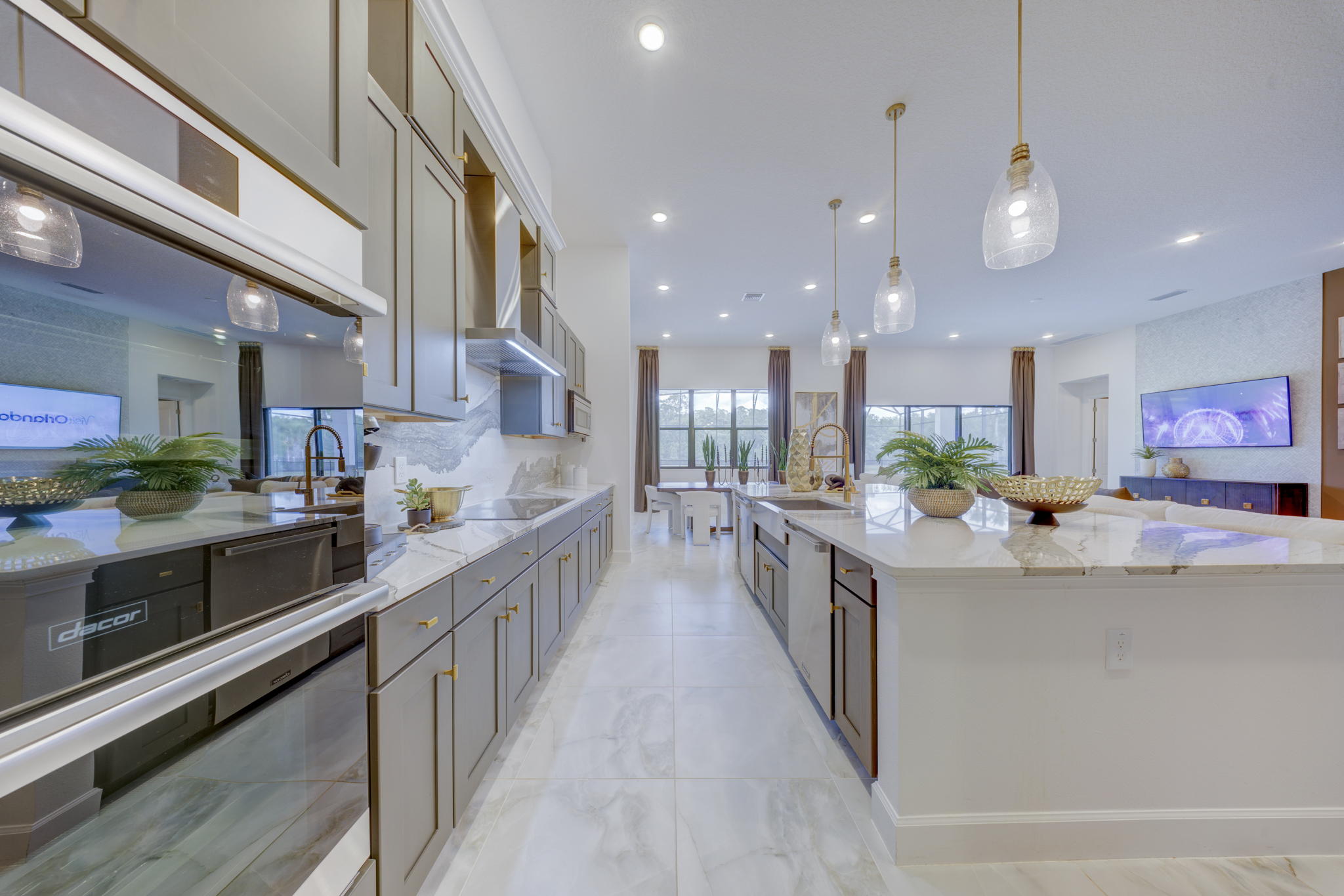 Chef's kitchen with gray cabinetry, Dacor double wall oven, marble backsplash and gold-accent pendant lights