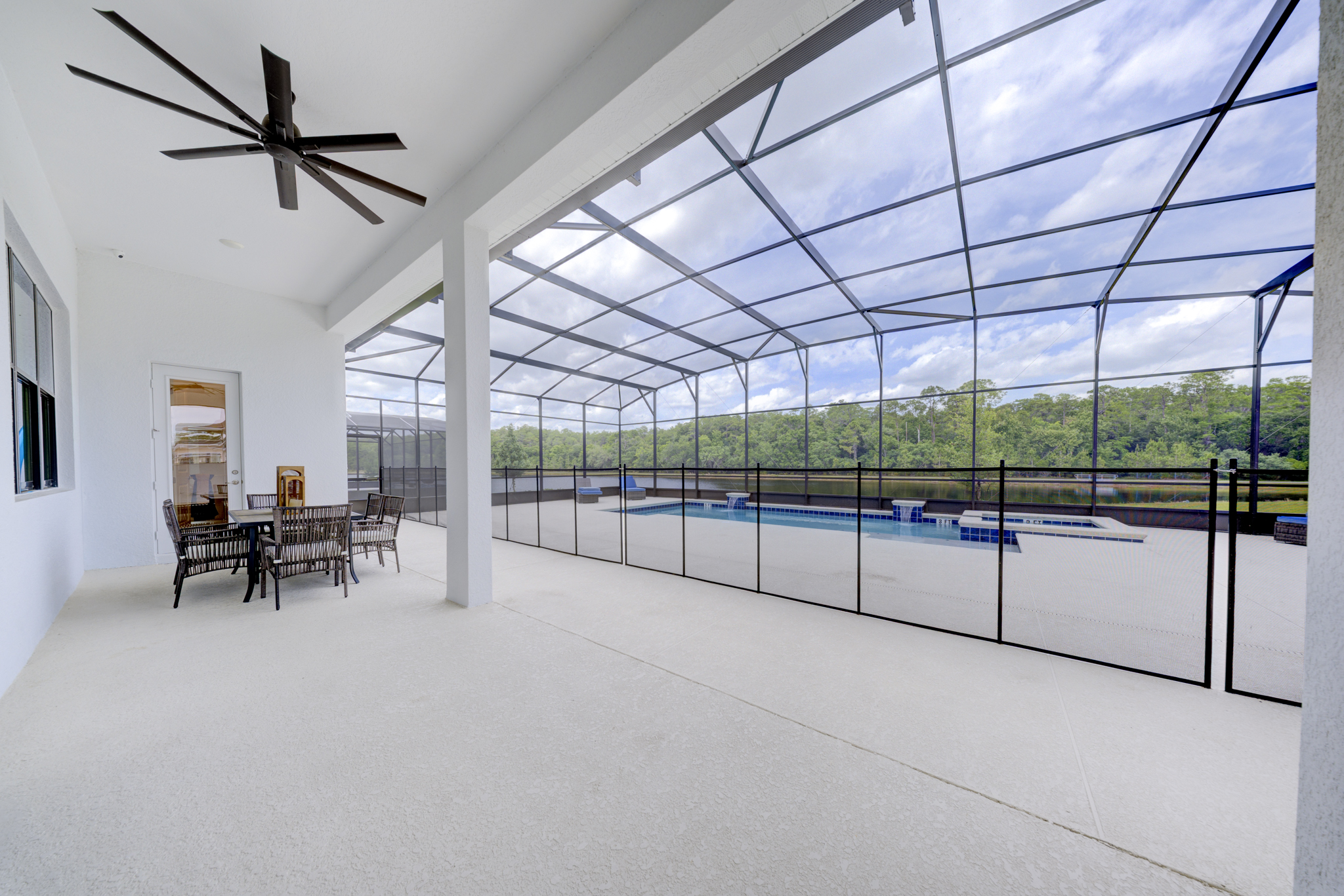 Covered lanai with ceiling fan, outdoor dining set and view of pool and lake through screen enclosure