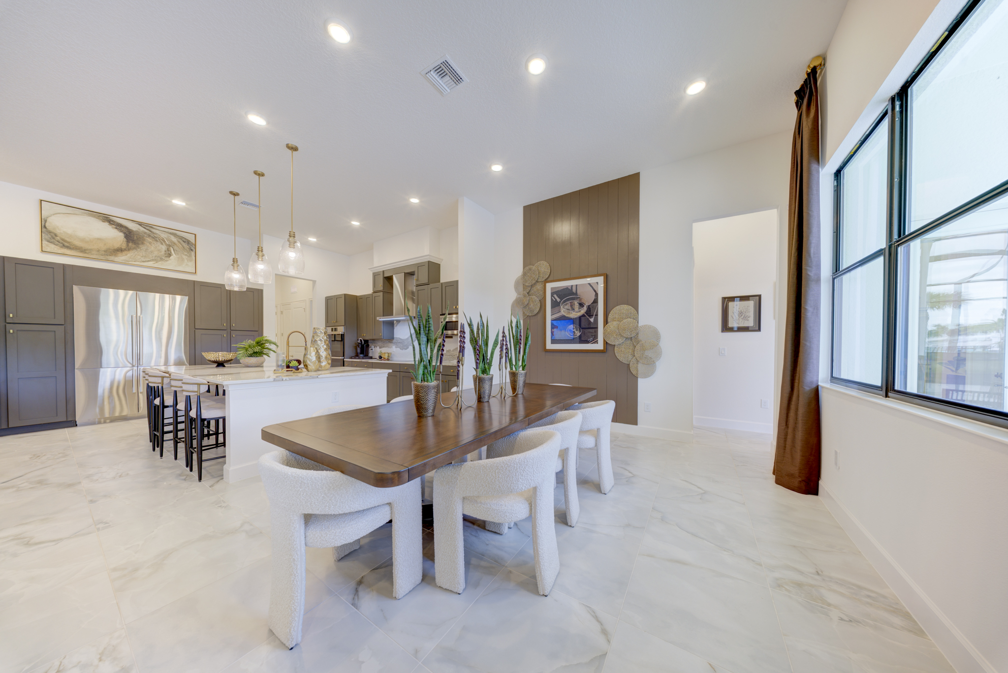 Dining area with live-edge wood table, boucle chairs and view to kitchen and pool beyond