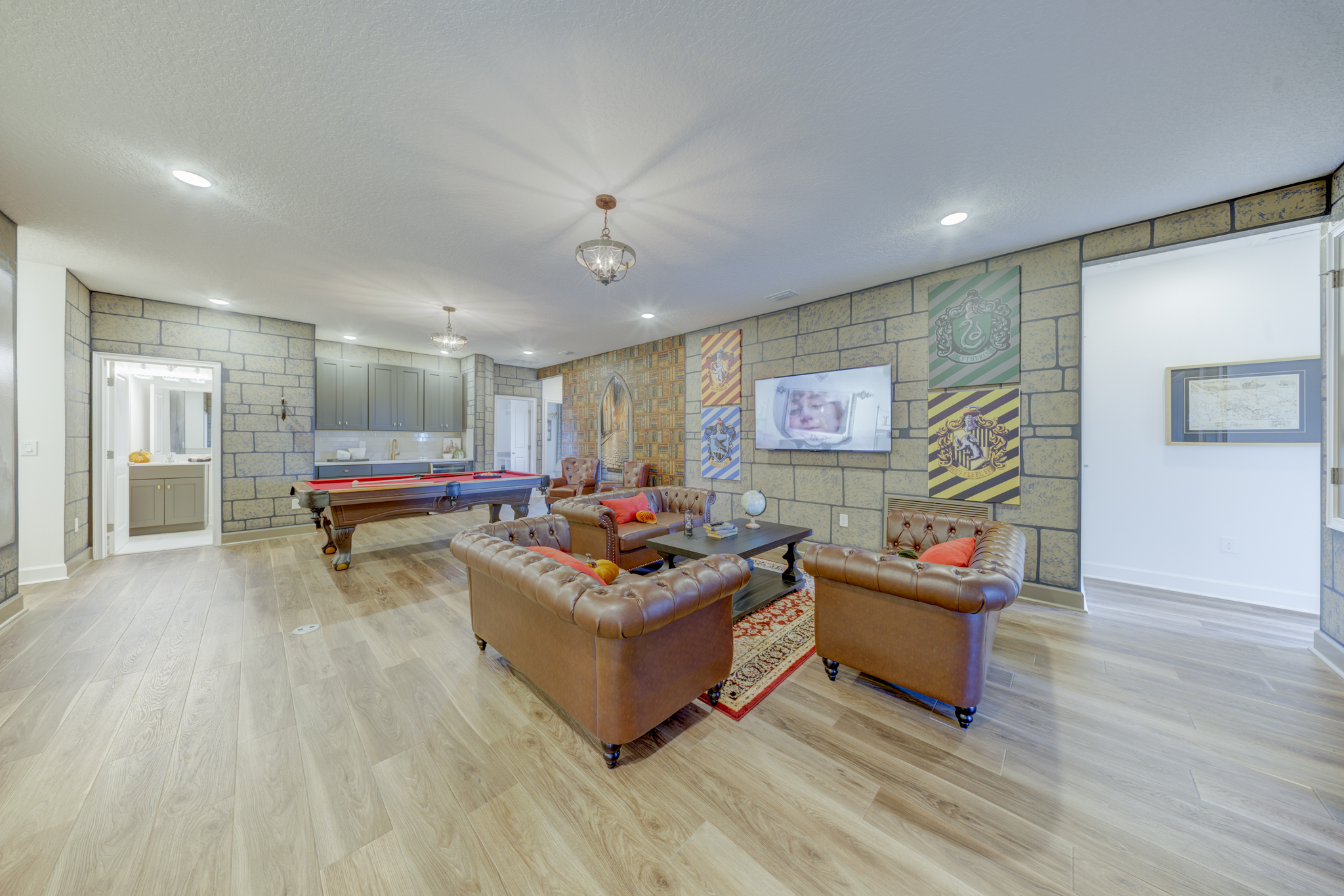 Game room alternate view showing pool table, leather Chesterfield seating, wet bar and Harry Potter décor