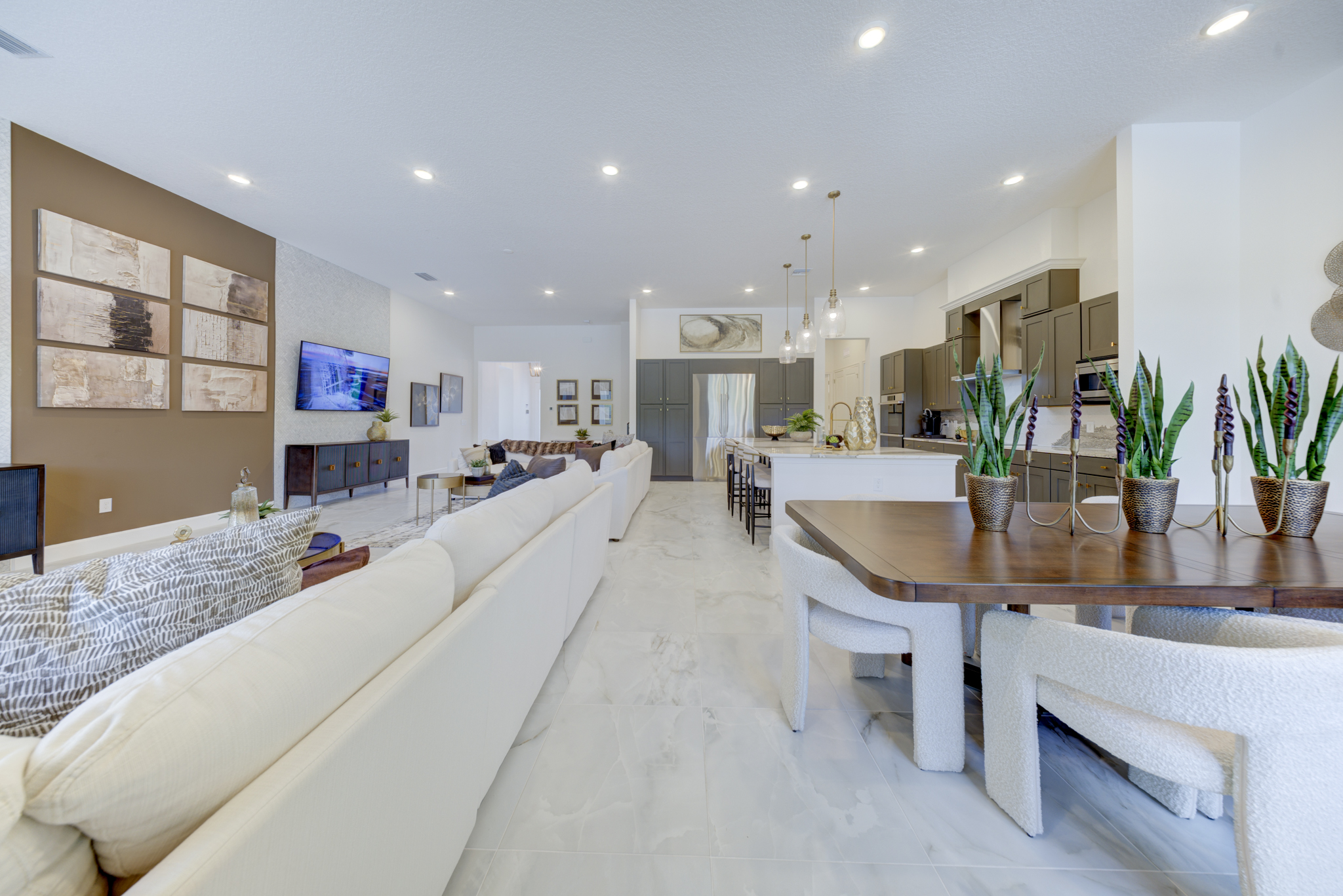 Open-plan living and dining with white sectional, wood dining table, boucle chairs and gray kitchen in background