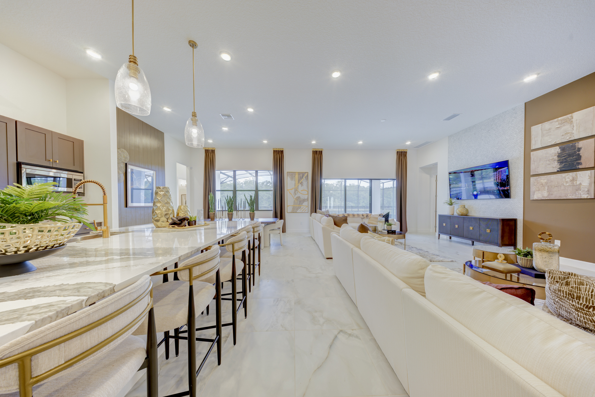 Kitchen island with marble waterfall countertop and pendant lights looking toward great room and dining area